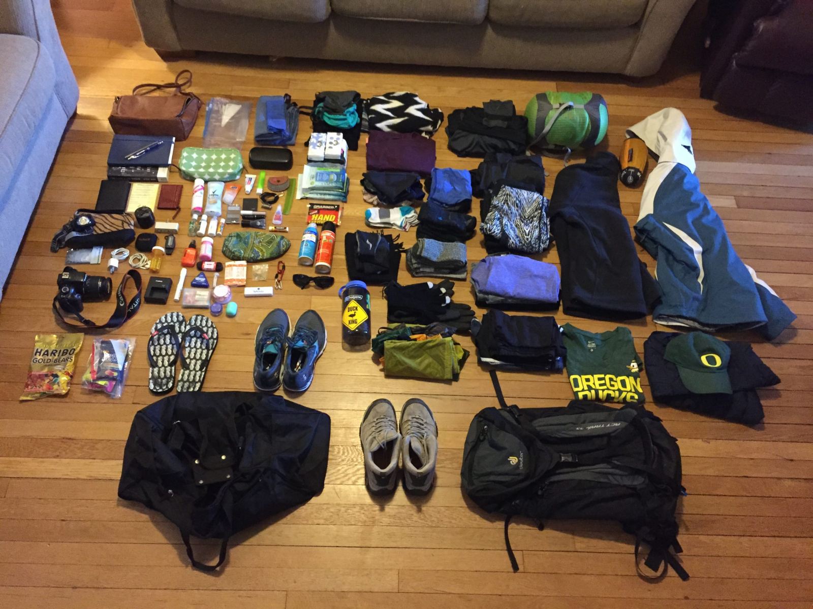 Climbing gear and clothes laid out on a floor before packing