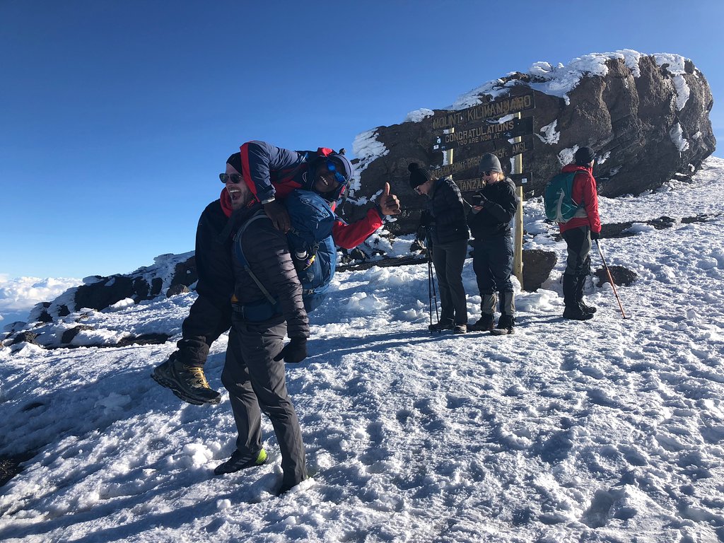 Climbers on a snowy summit trail on Kilimanjaro under a blue sky