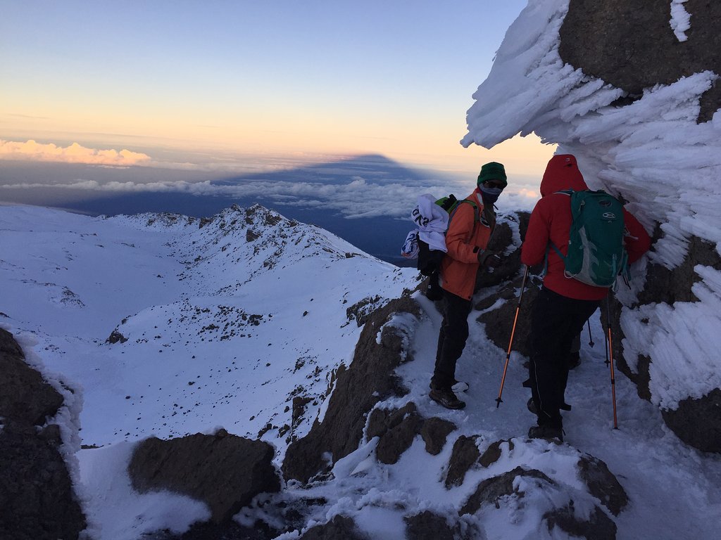 Two climbers resting beside an ice wall near the summit of Kilimanjaro