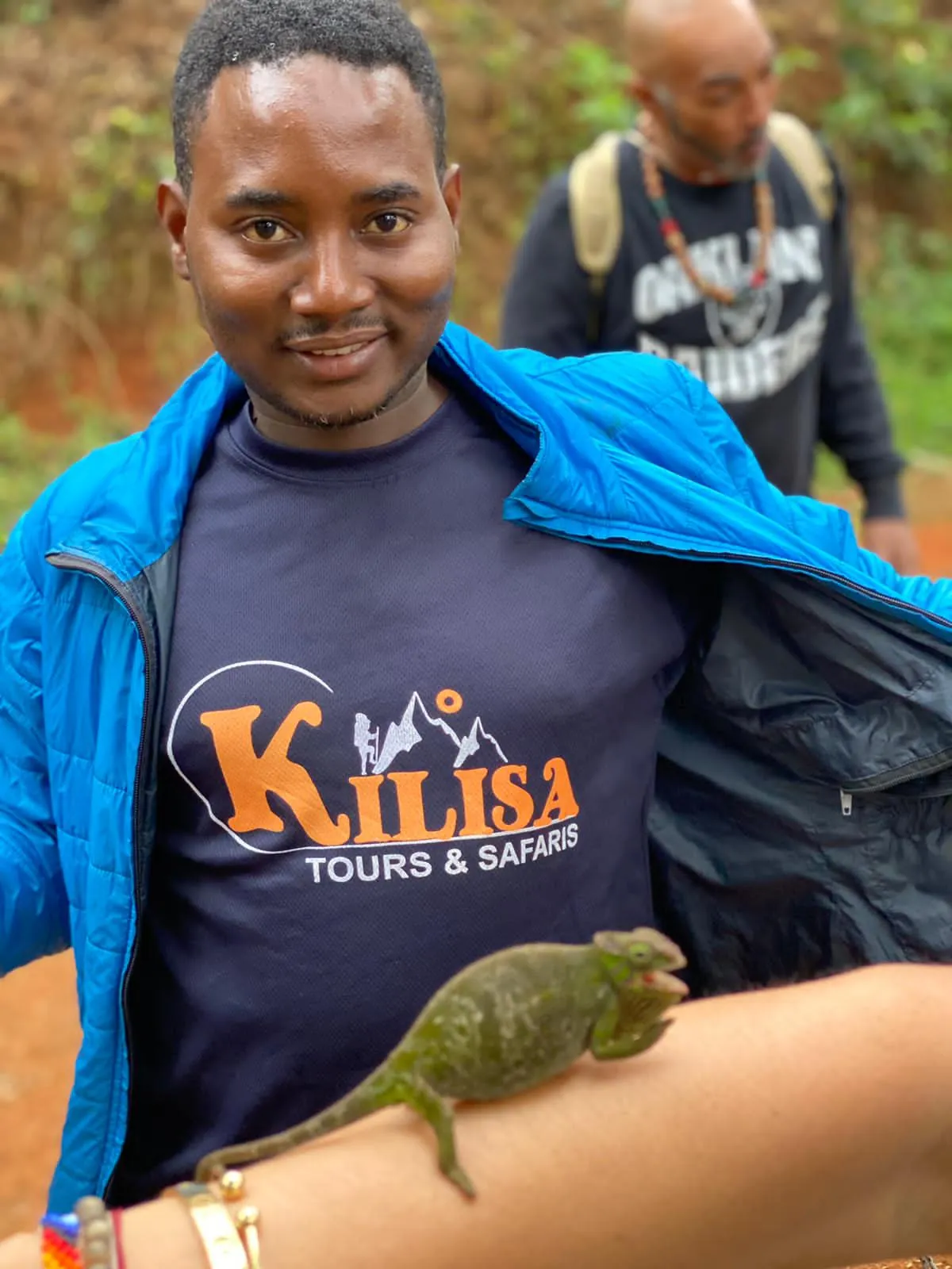 Kilisa Tours guide with a green chameleon perched on his arm during a nature walk in Tanzania