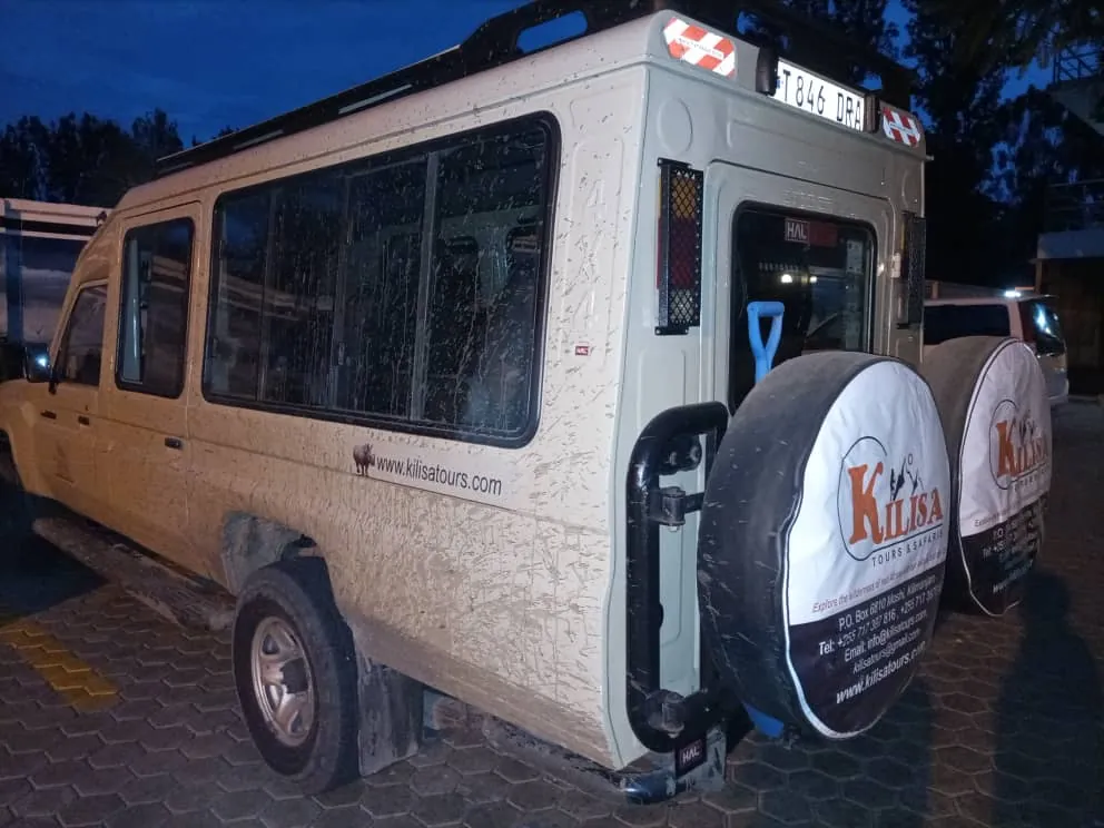 Kilisa Tours safari Land Cruiser with branded spare wheel covers parked at dusk