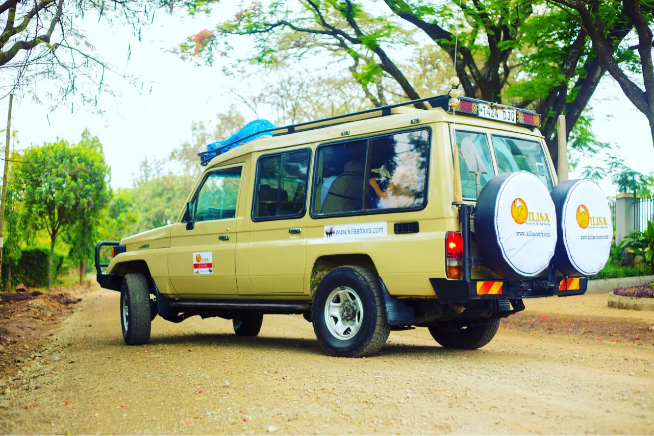 Kilisa Tours safari Land Cruiser loaded for departure on a tree-lined road in Moshi, Tanzania